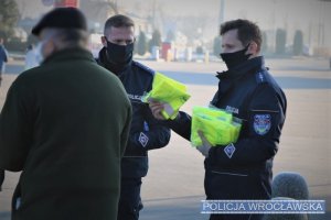 policjanci przekazują odblaskowe kamizelki