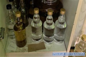 Zdjęcia przedstawiają beczki oraz butelki z nielegalnym alkoholem