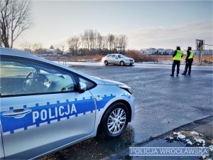 Zdjęcia przedstawiają policjantów kontrolujących pojazdy. Widoczni są funkcjonariusze w granatowych mundurach i żółtych odblaskowych, kamizelkach.