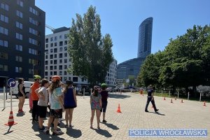 Uczniowie z policjantem stojący na torze przeszkód