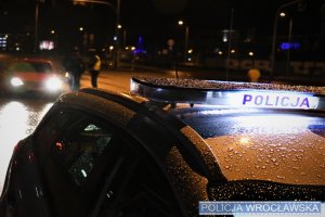 Dach radiowozu nocą z podświetlonym napisem Policja